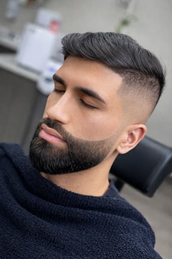 Brushed-back skin fade blended into a full beard