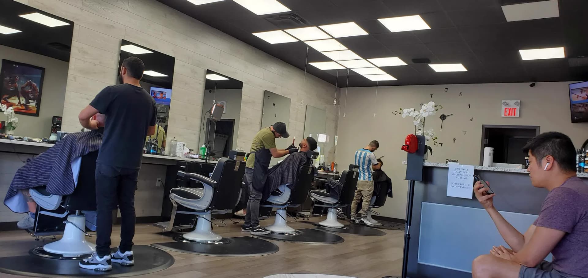 Three barbers working the floor on a busy afternoon
